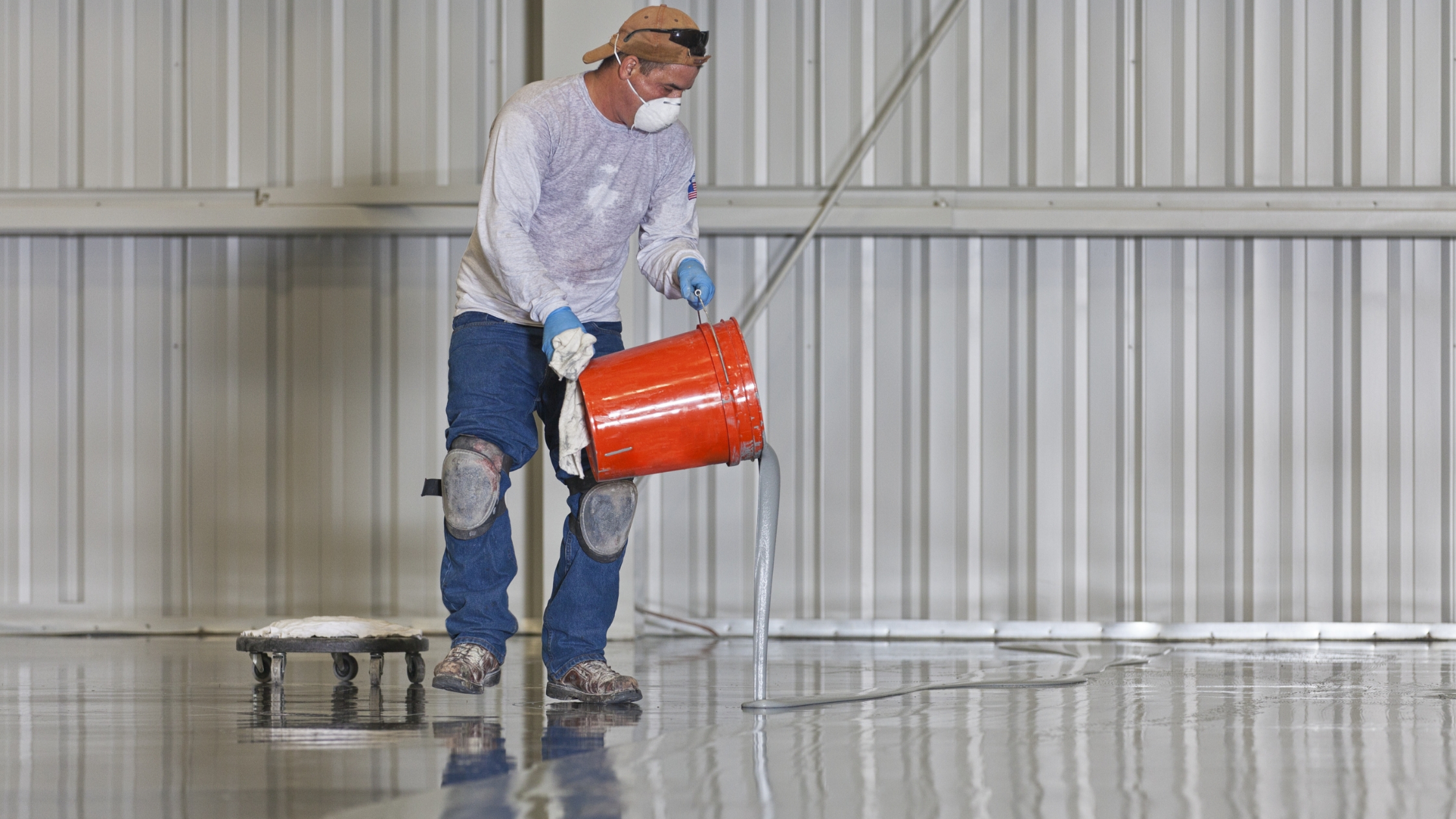 man pouring resinous floor coating